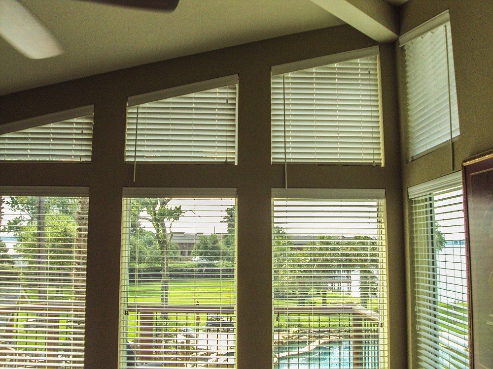 A room with a lot of windows with blinds and a ceiling fan