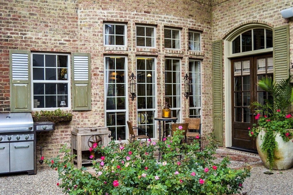A brick house with a grill and flowers in front of it.