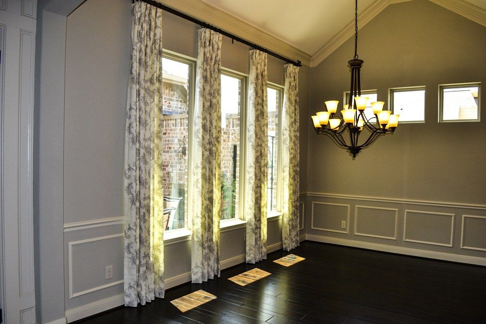 An empty dining room with a chandelier and lots of windows