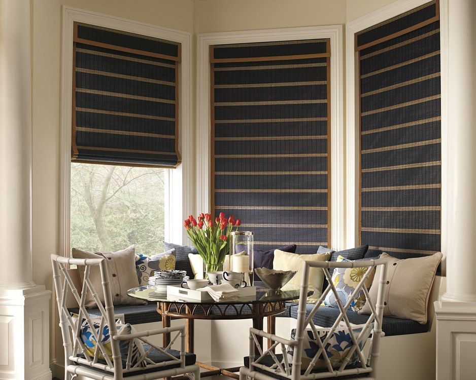 A dining room with a table and chairs in a bay window.