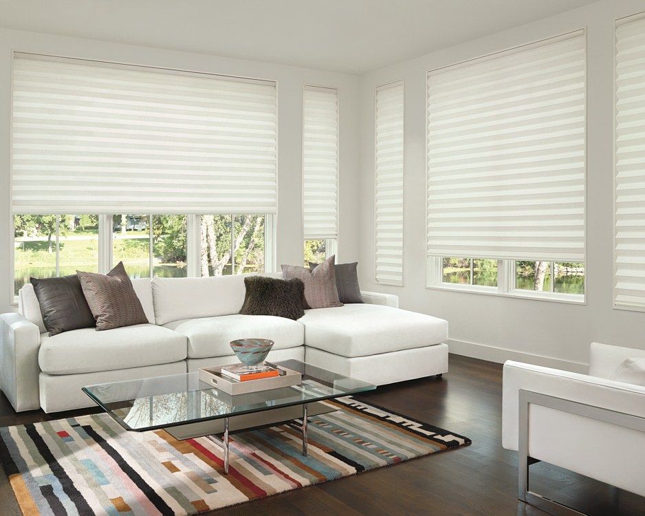 A living room with a white couch , chair , coffee table and striped rug.