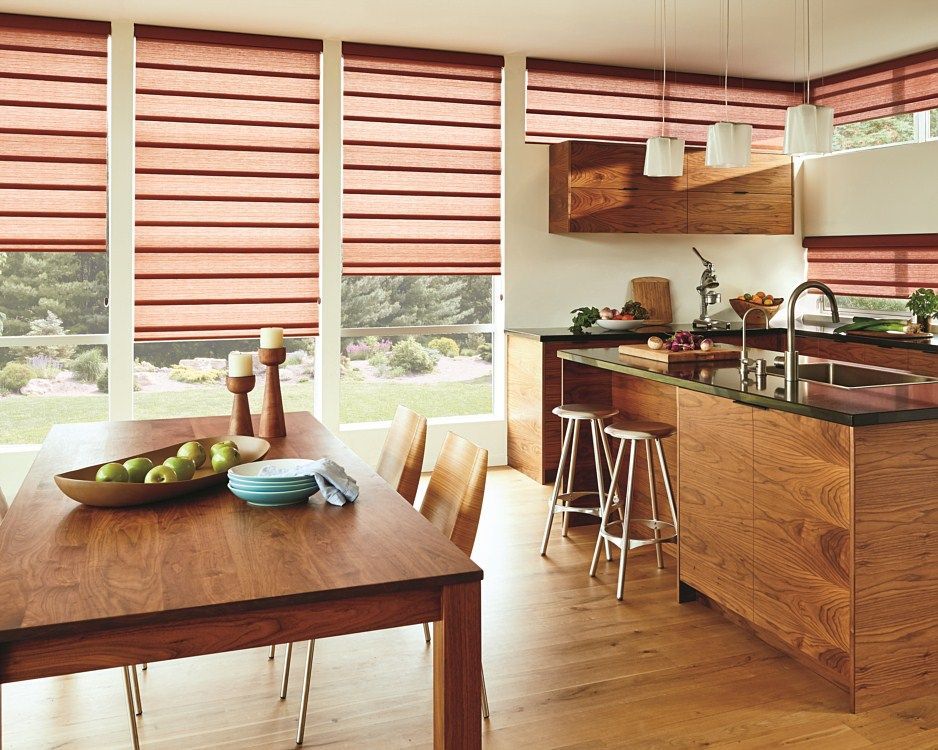 A kitchen with a table and chairs and a bowl of apples on the table.