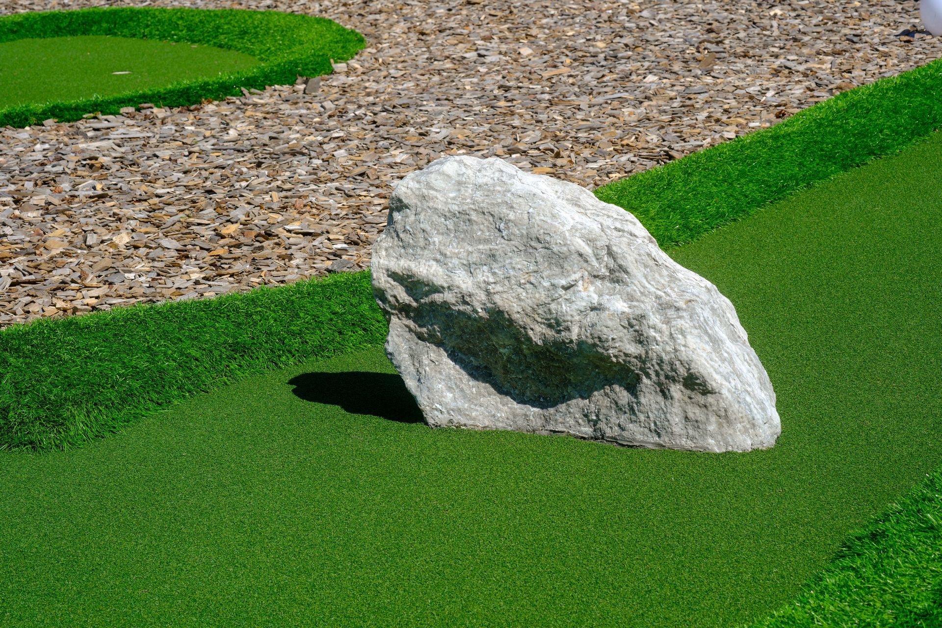 White rock on bright green turf beside a gravel path
