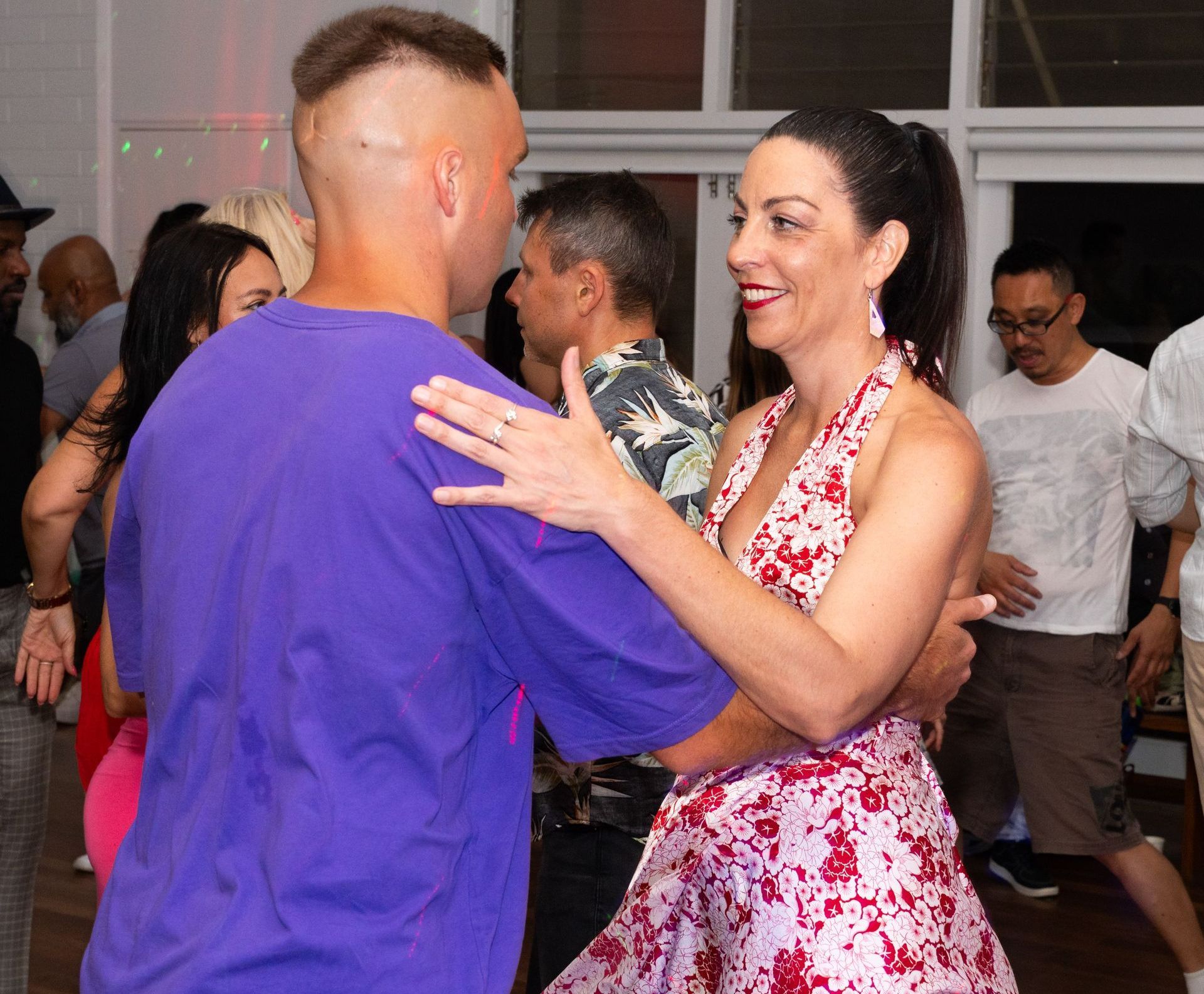 A man in a purple shirt is dancing with a woman in a pink dress.