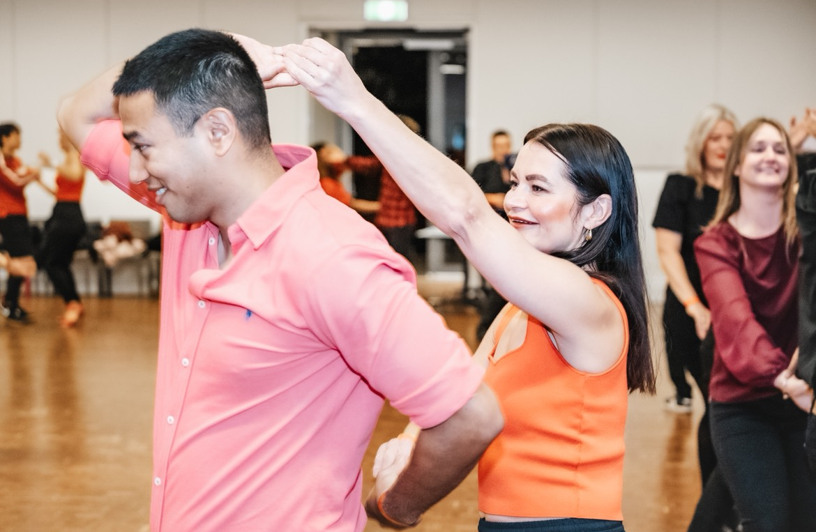 A man and a woman are dancing together on a gray background.