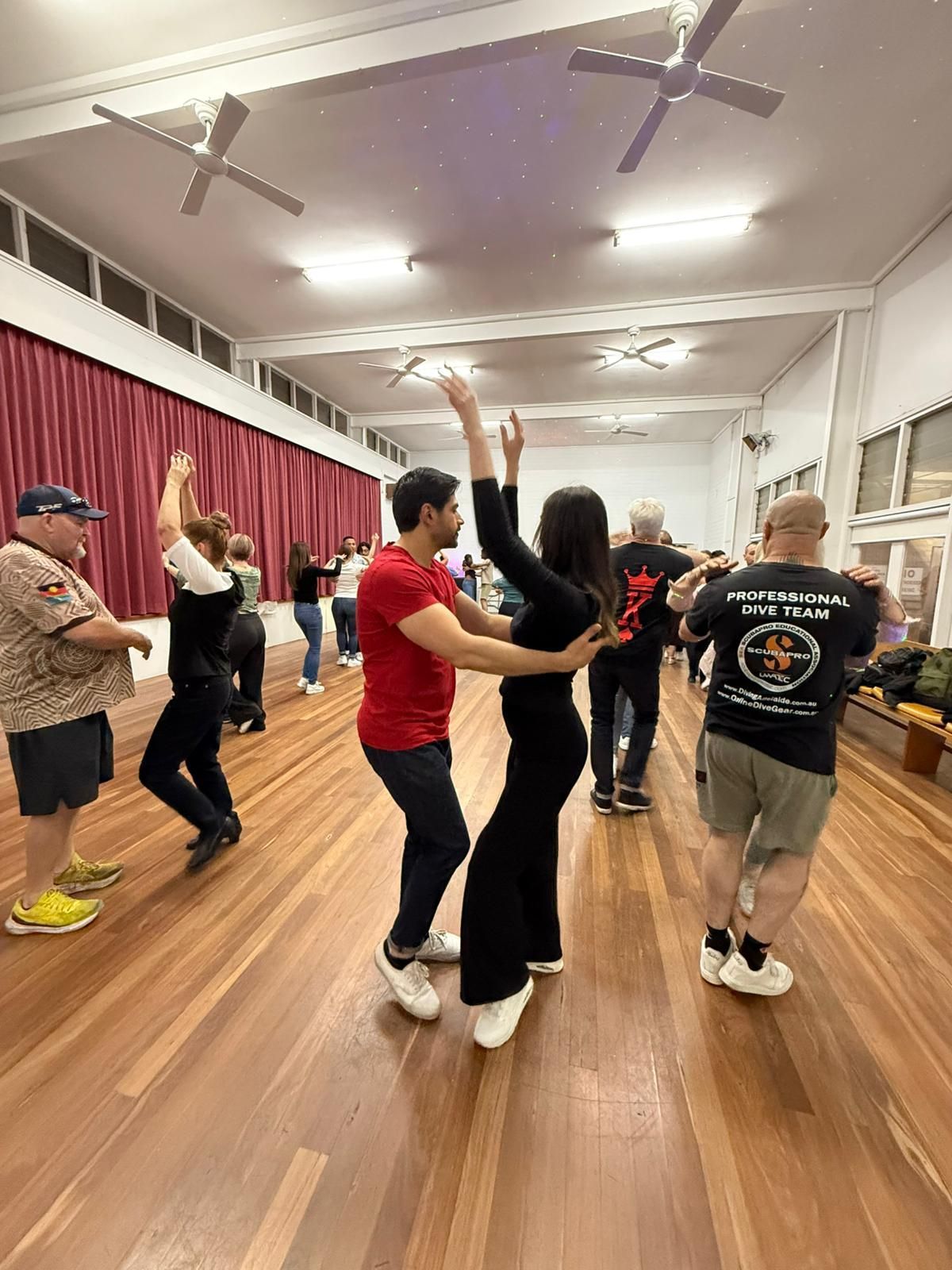 A man and a woman are dancing together on a gray background.