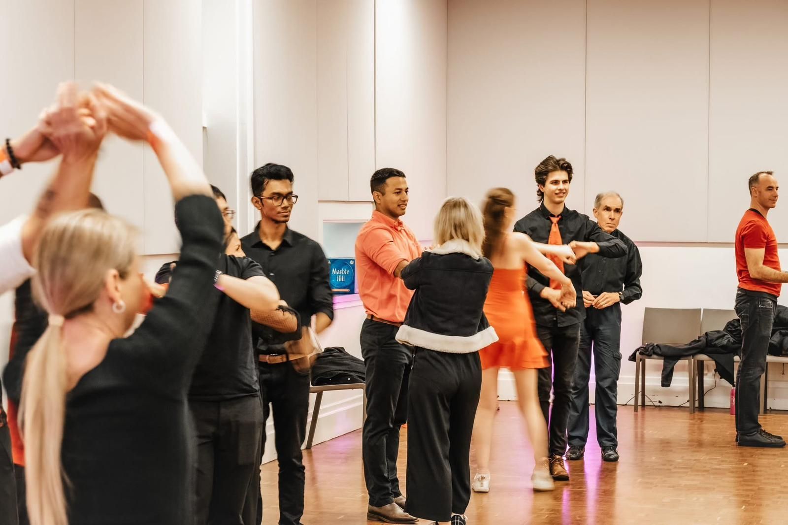 A man and two women are posing for a picture in front of a red curtain.
