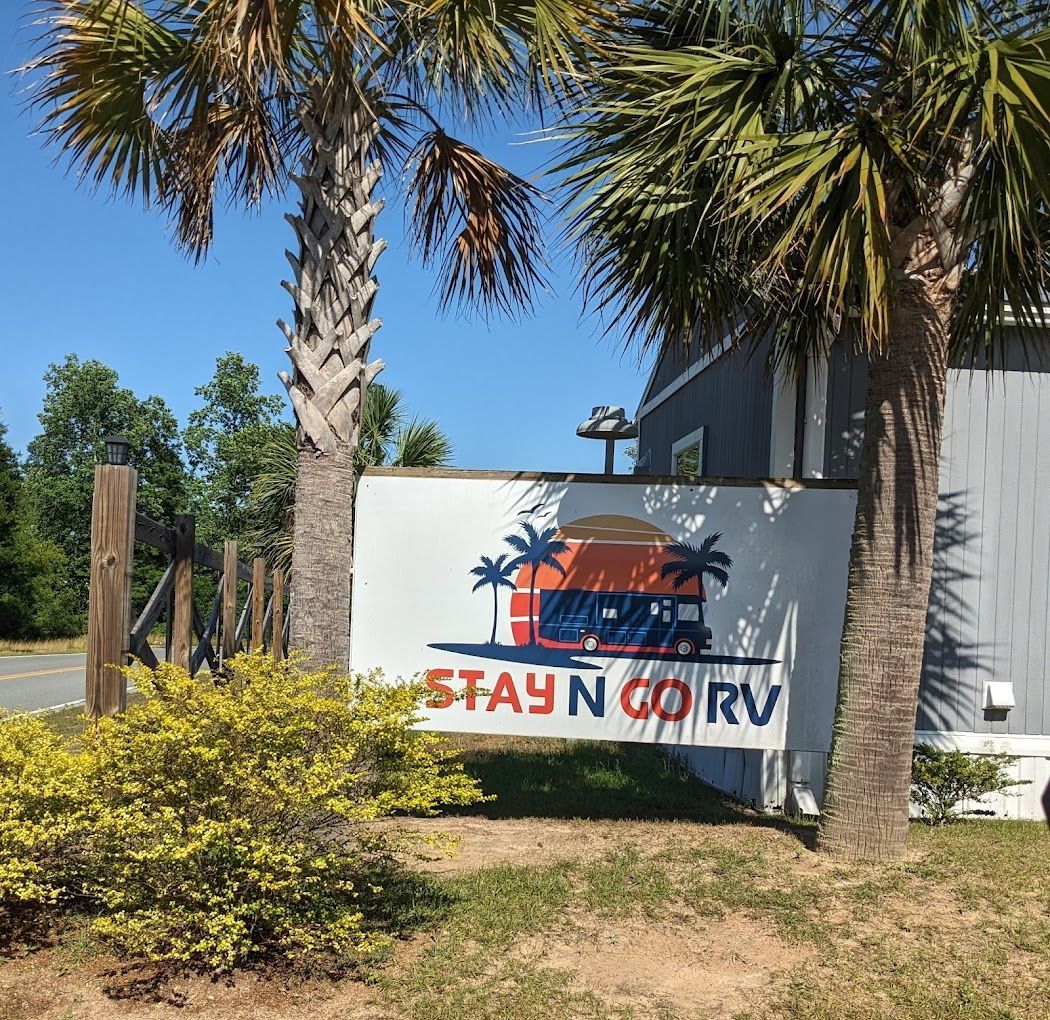 A sign that says `` stay n go rv '' is surrounded by palm trees.