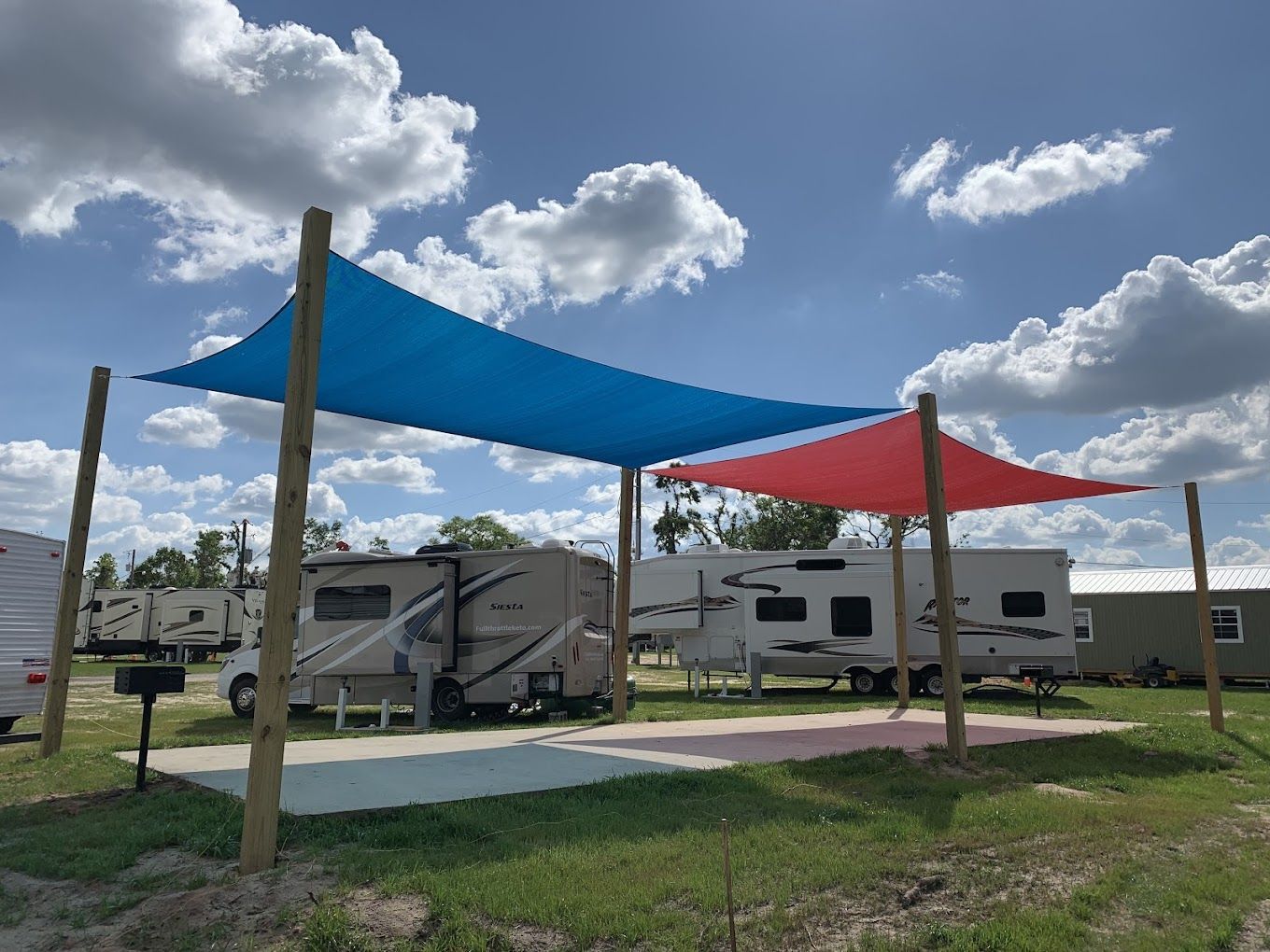 A row of rvs parked under a blue and red canopy.
