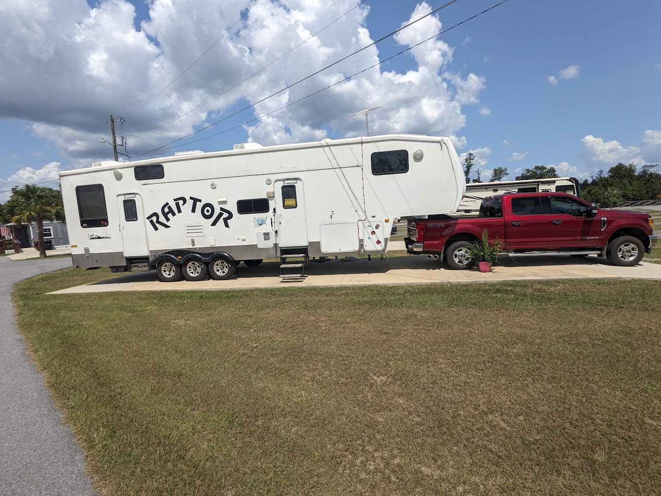 A red truck is parked next to a white trailer.