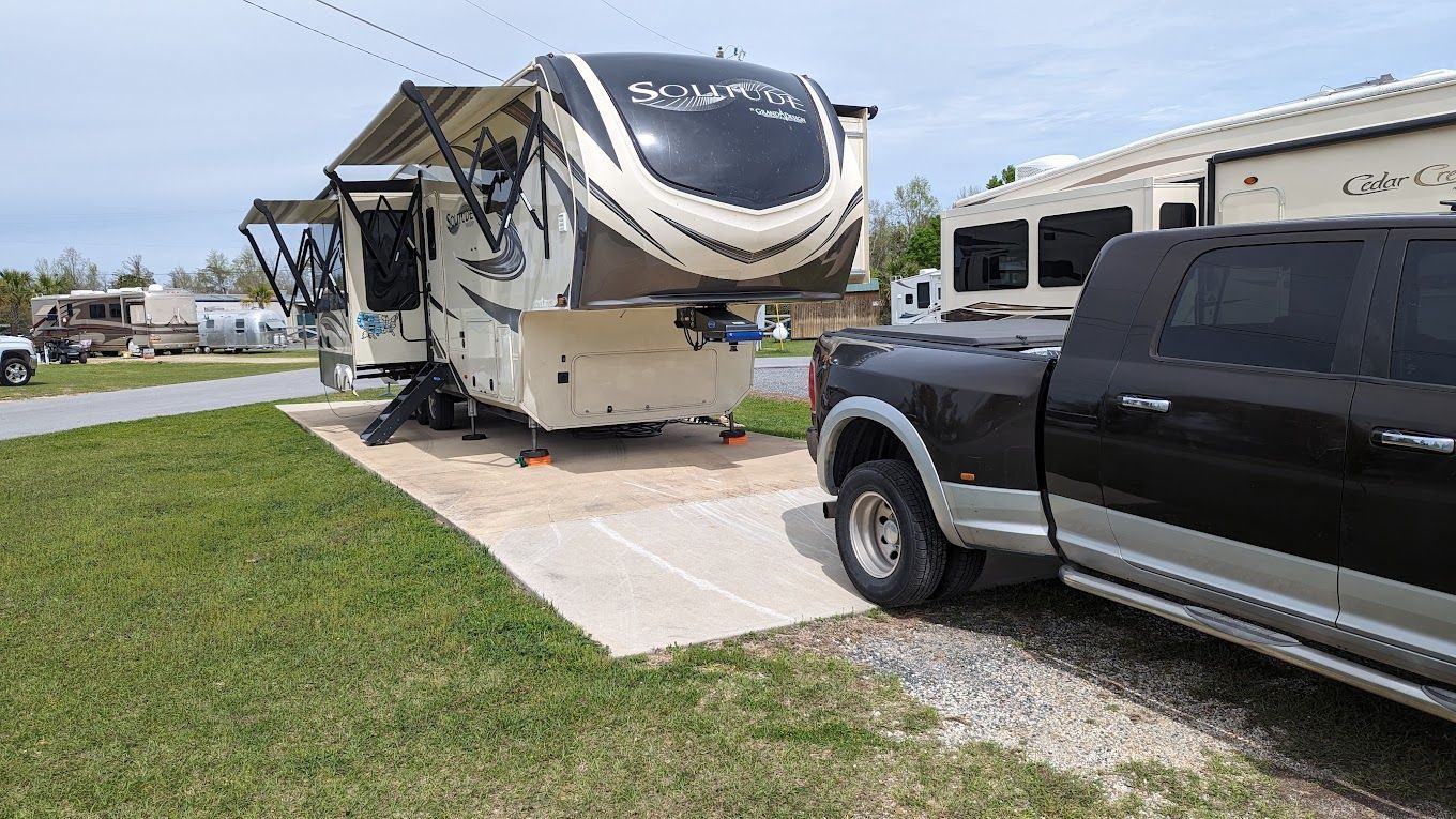 A truck is parked next to a rv in a parking lot.