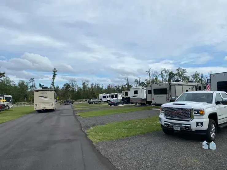 A white truck is parked on the side of a road next to a row of rvs.