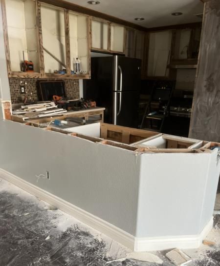 A kitchen is being remodeled with a black refrigerator.