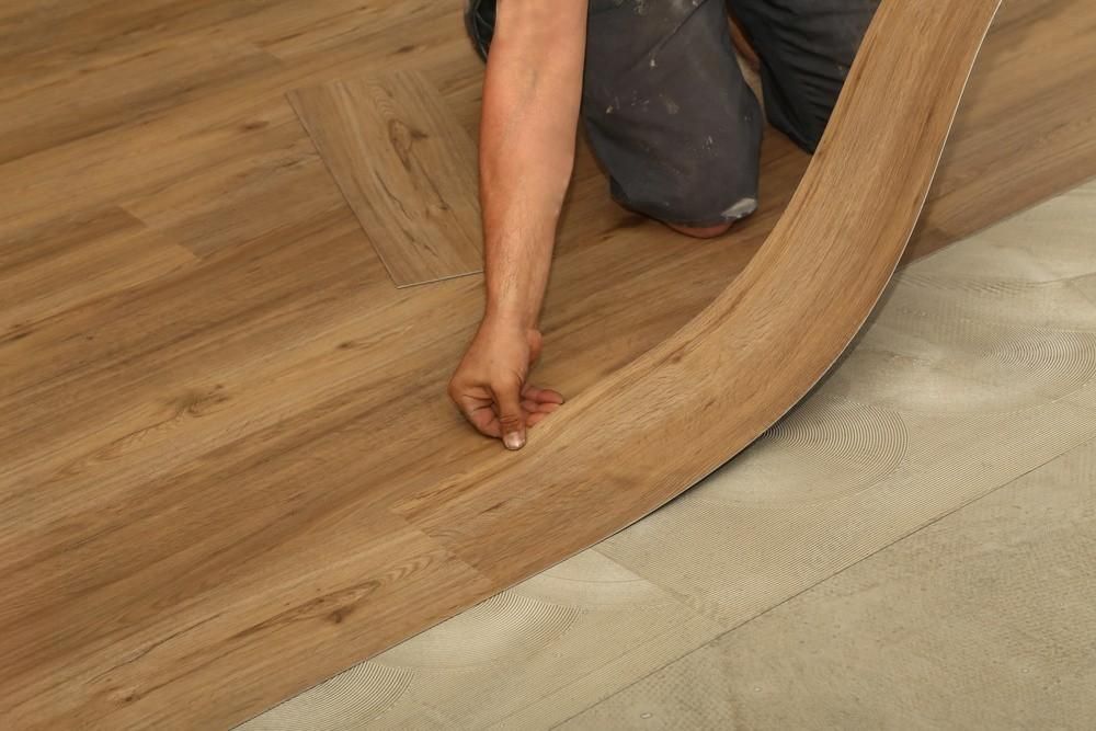 A person is installing a wooden floor in a room.