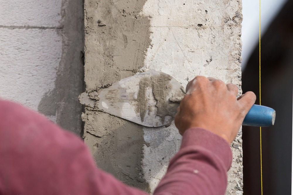 A man is plastering a wall with a trowel.