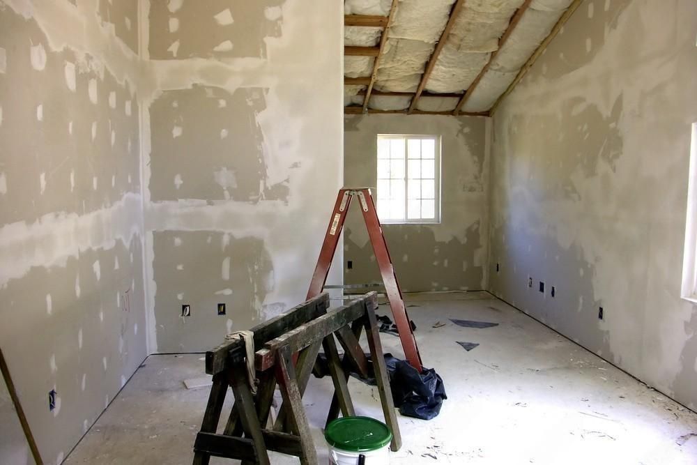 An empty room with a ladder and a bucket of paint