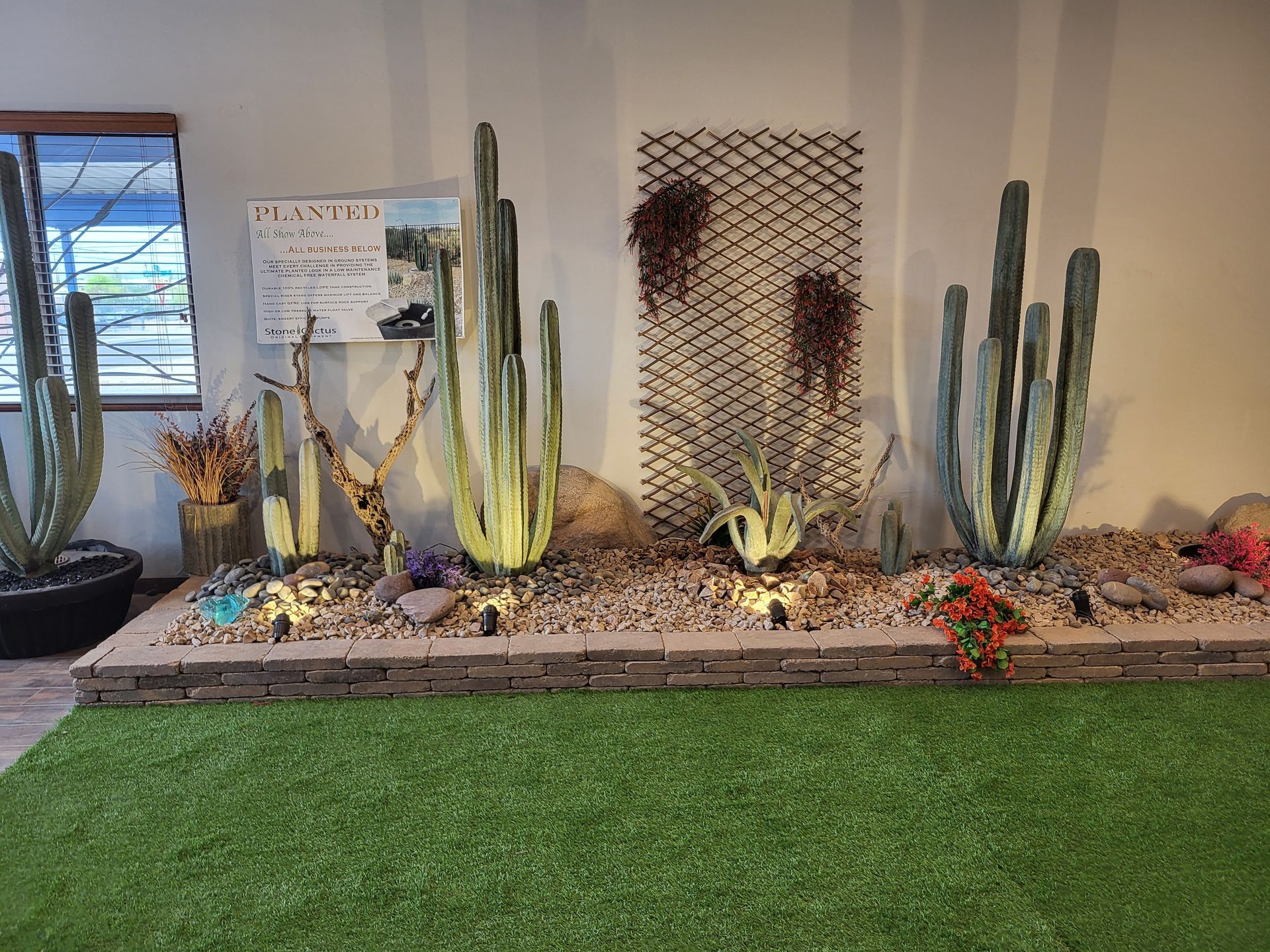 A row of cactus plants sitting on top of a lush green lawn in a room.