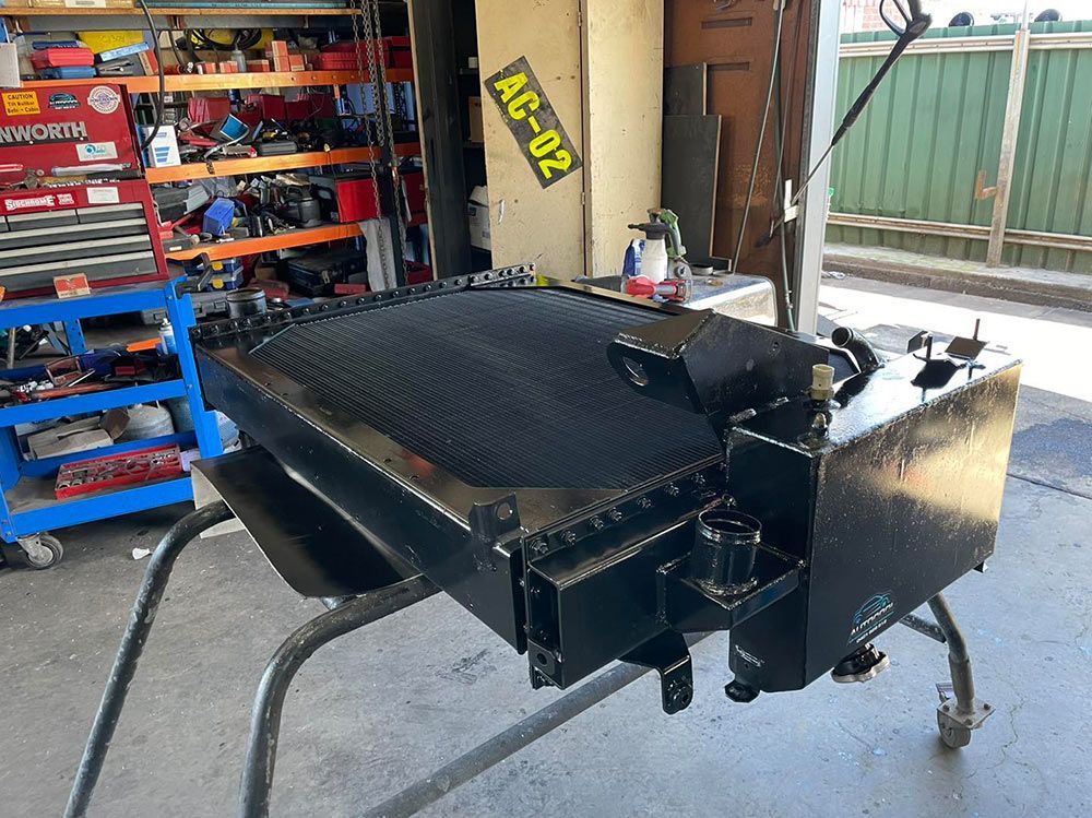 A Black Radiator Is Sitting On A Metal Stand In A Garage — Autocool Air Conditioning in Raymond Terrace, NSW