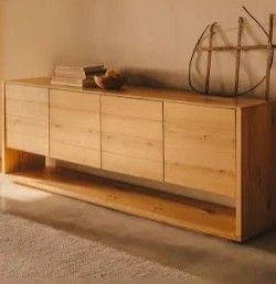 Credenza in legno con libri e oggetti decorativi in una stanza calda e minimalista.