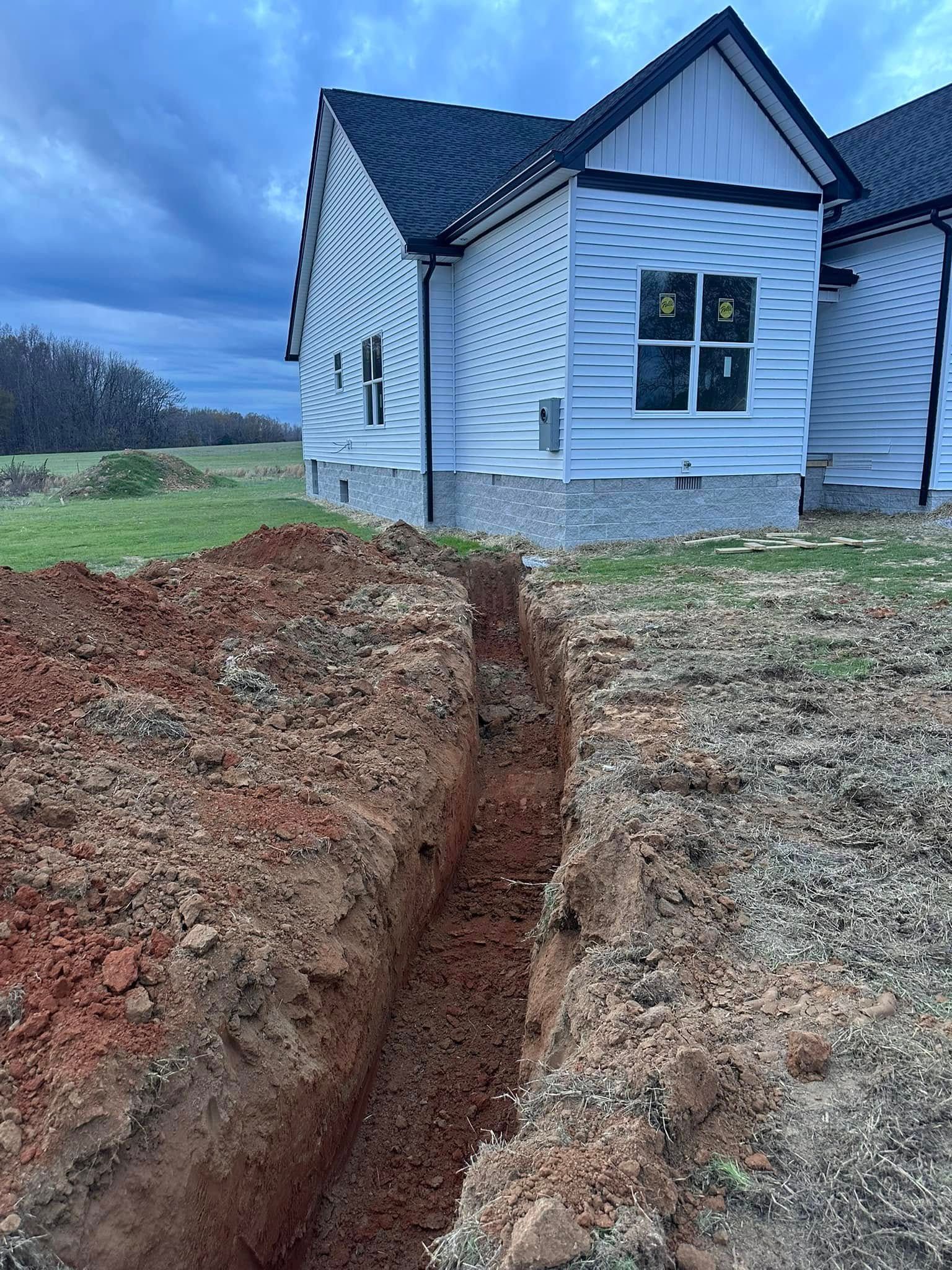 A large hole in the ground in front of a house.