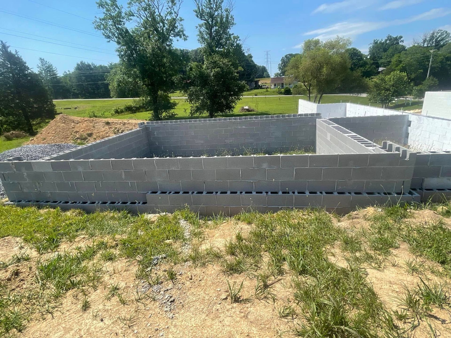 A large brick wall is sitting in the middle of a grassy field.