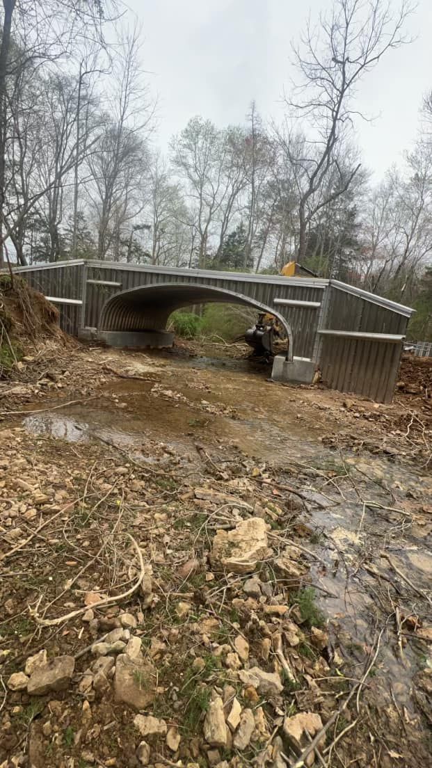 A bridge is being built over a muddy stream in the middle of a forest.