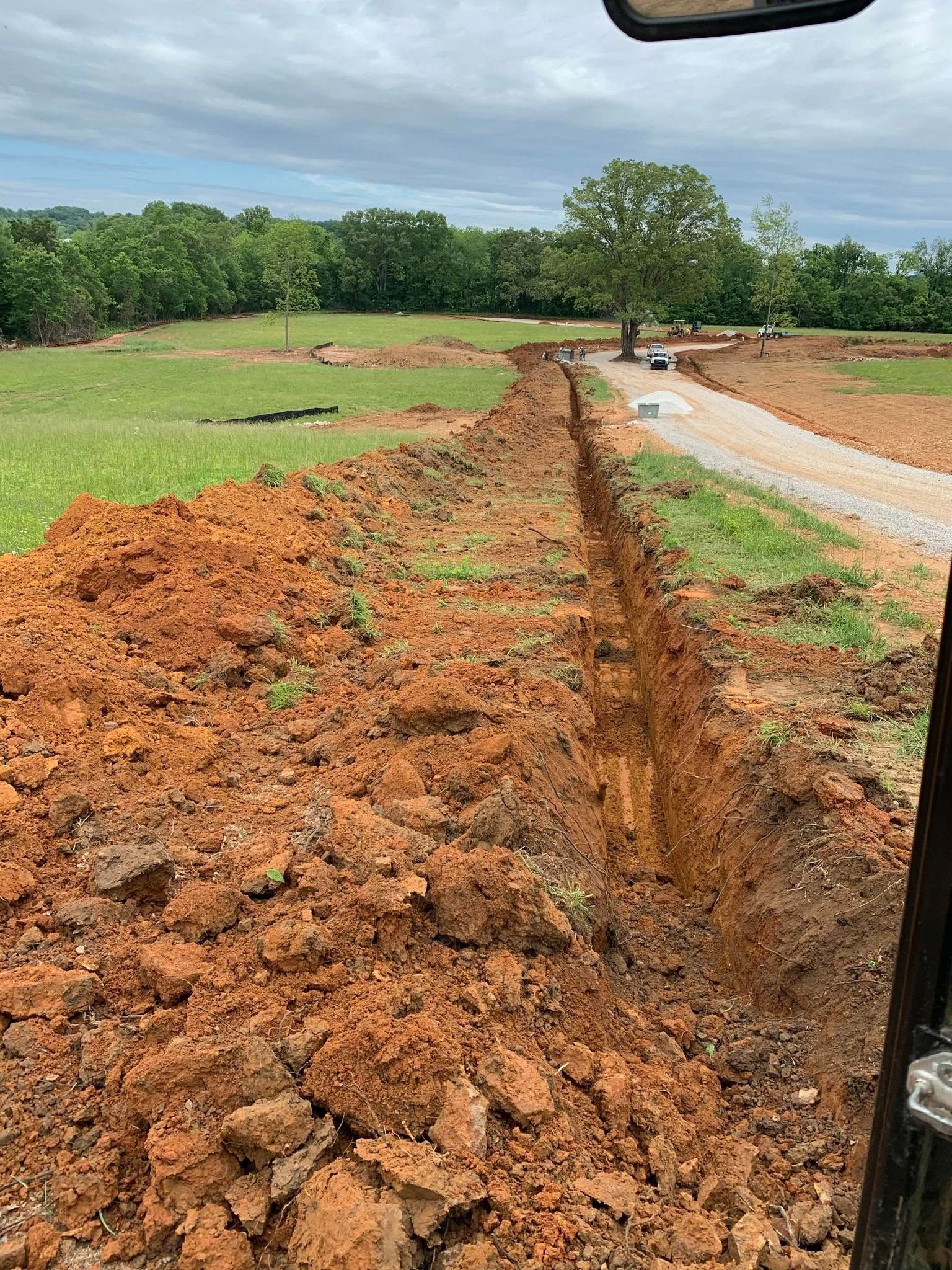 A large pile of dirt is sitting next to a road in a field.