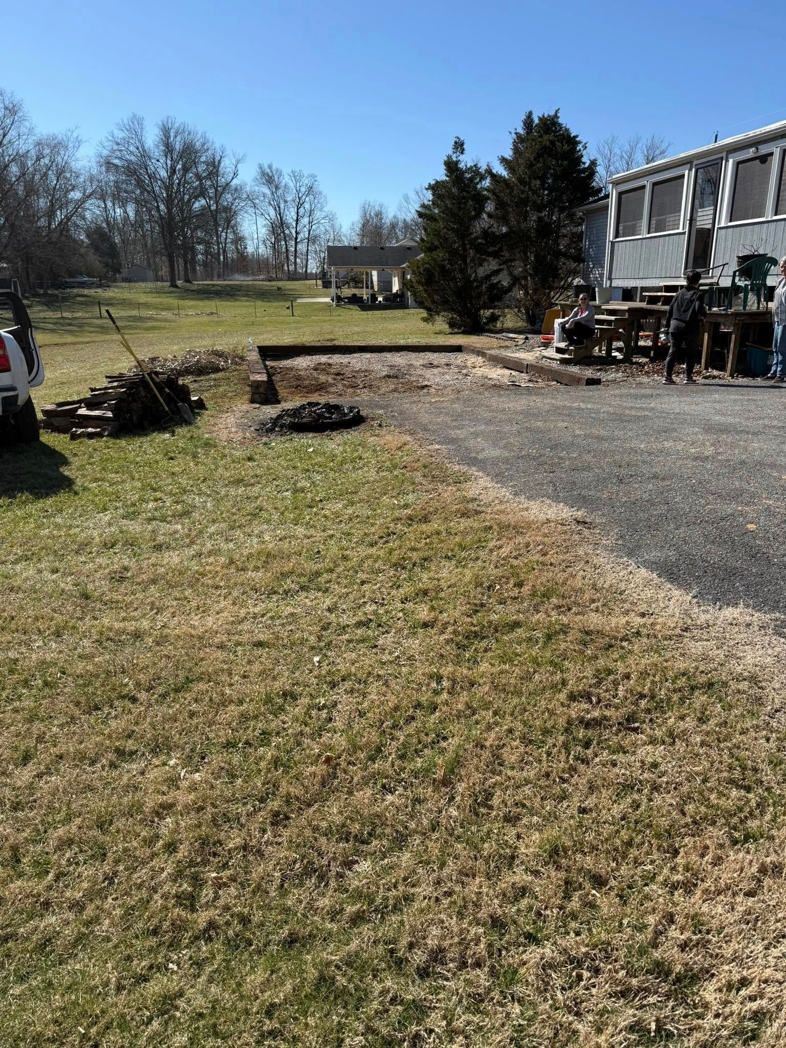 A truck is parked in a grassy field in front of a house.