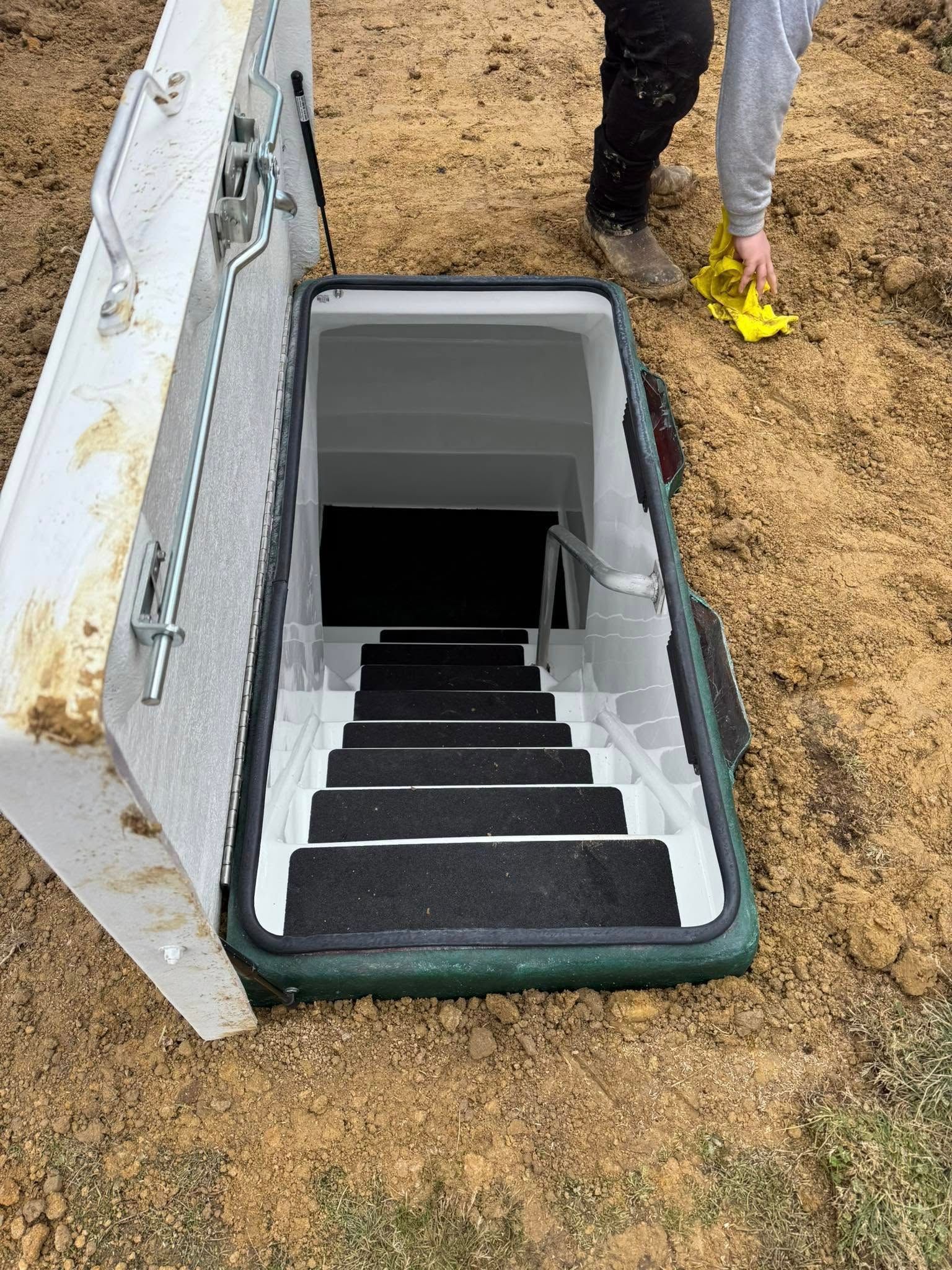A person is standing next to a bunker with stairs leading up to it.