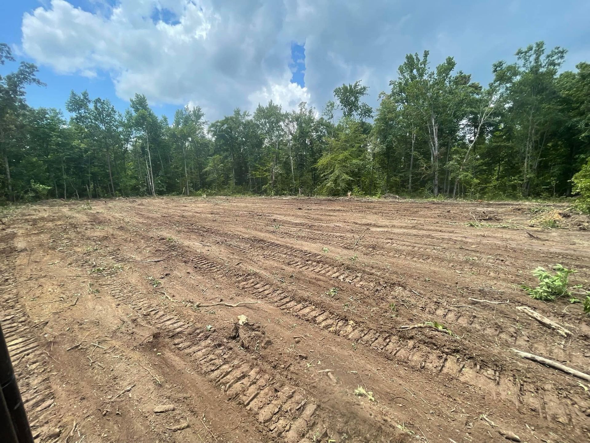 A large dirt field with trees in the background.