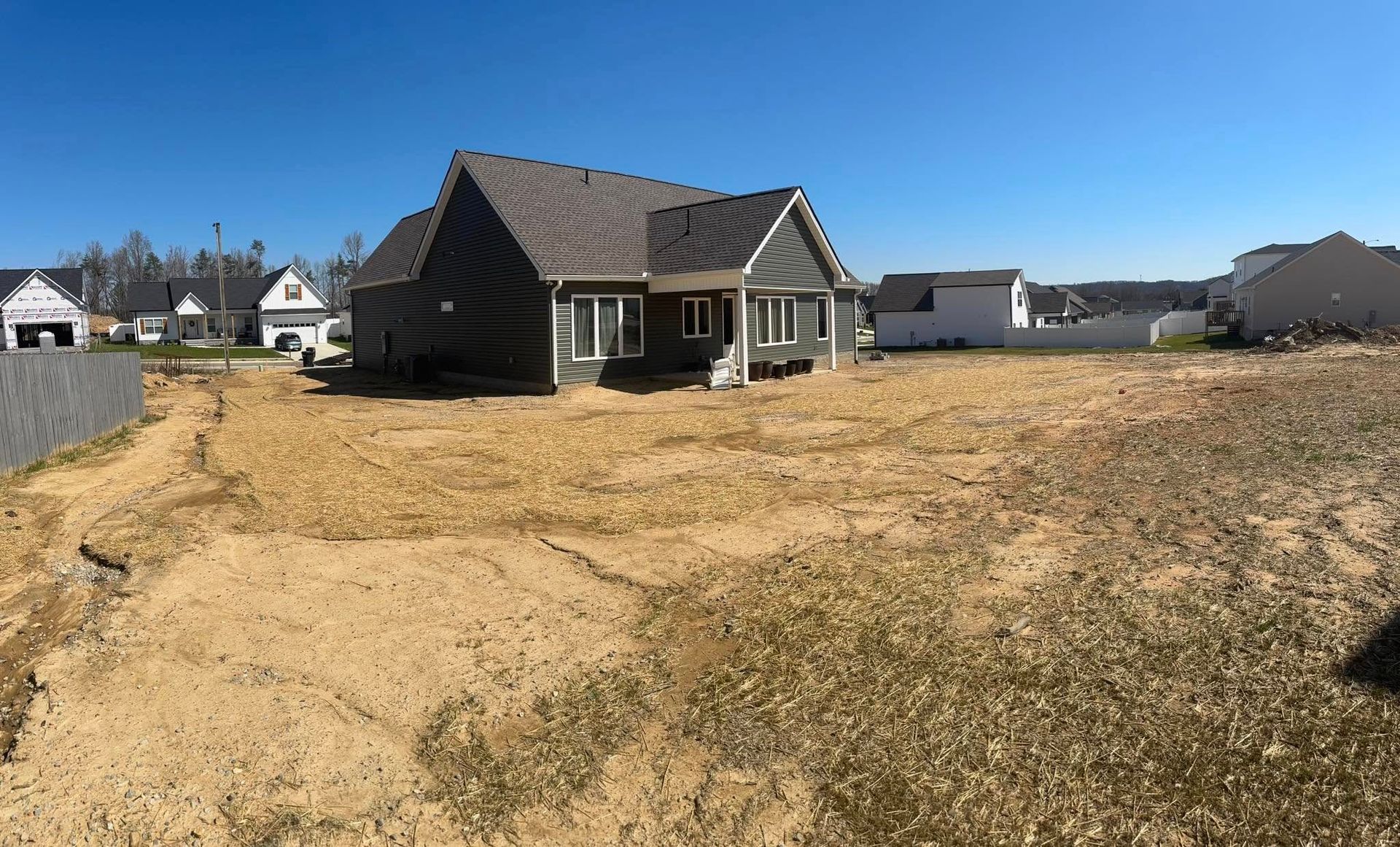 A house is sitting in the middle of a dirt field.