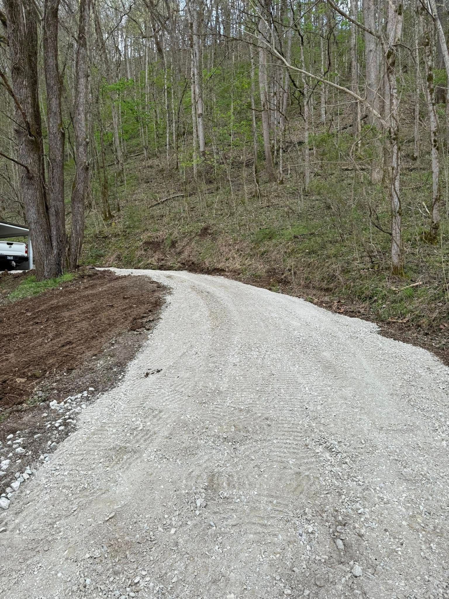A gravel road going through a forest with trees on both sides.