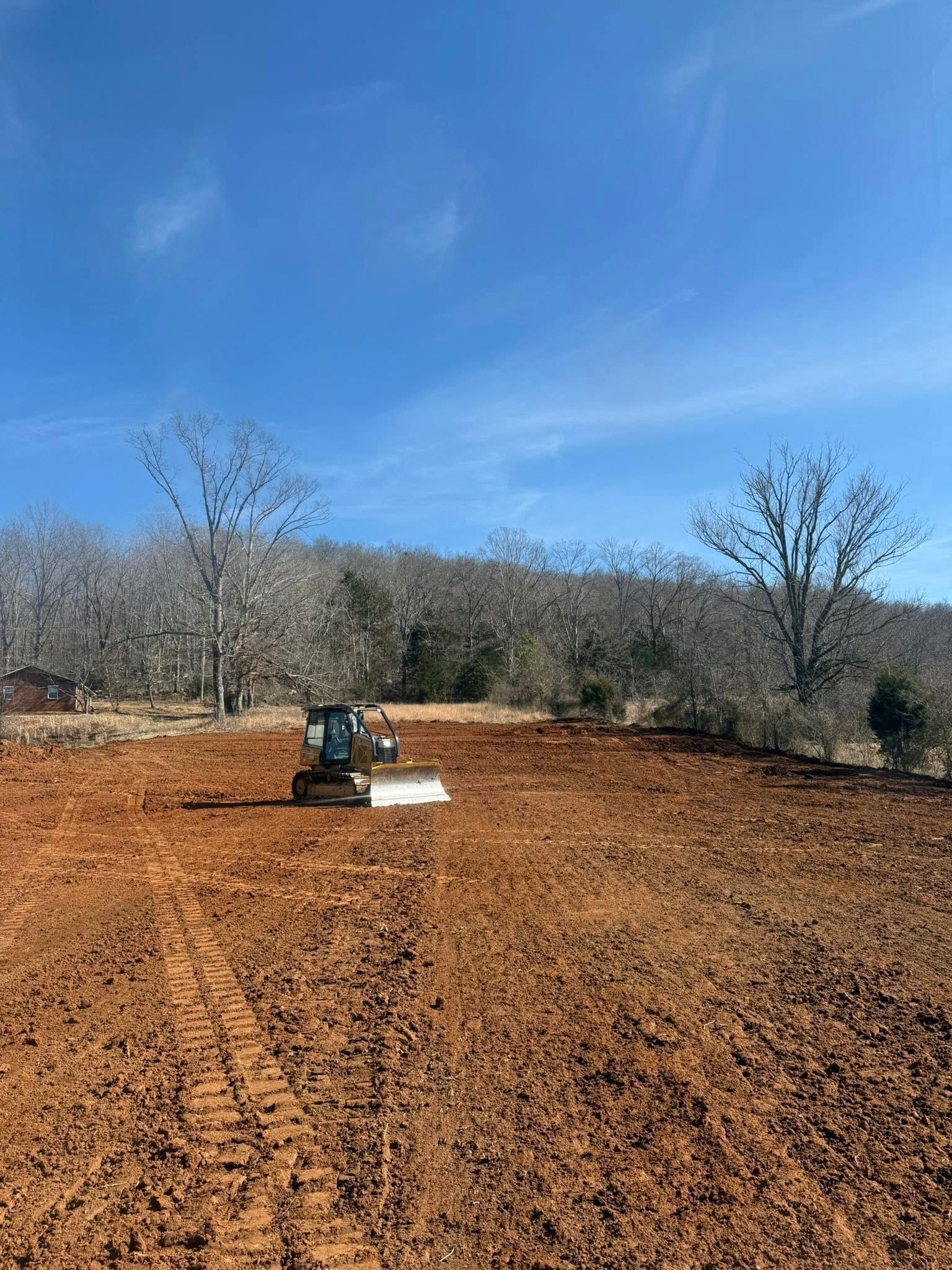 A bulldozer is sitting in the middle of a dirt field.