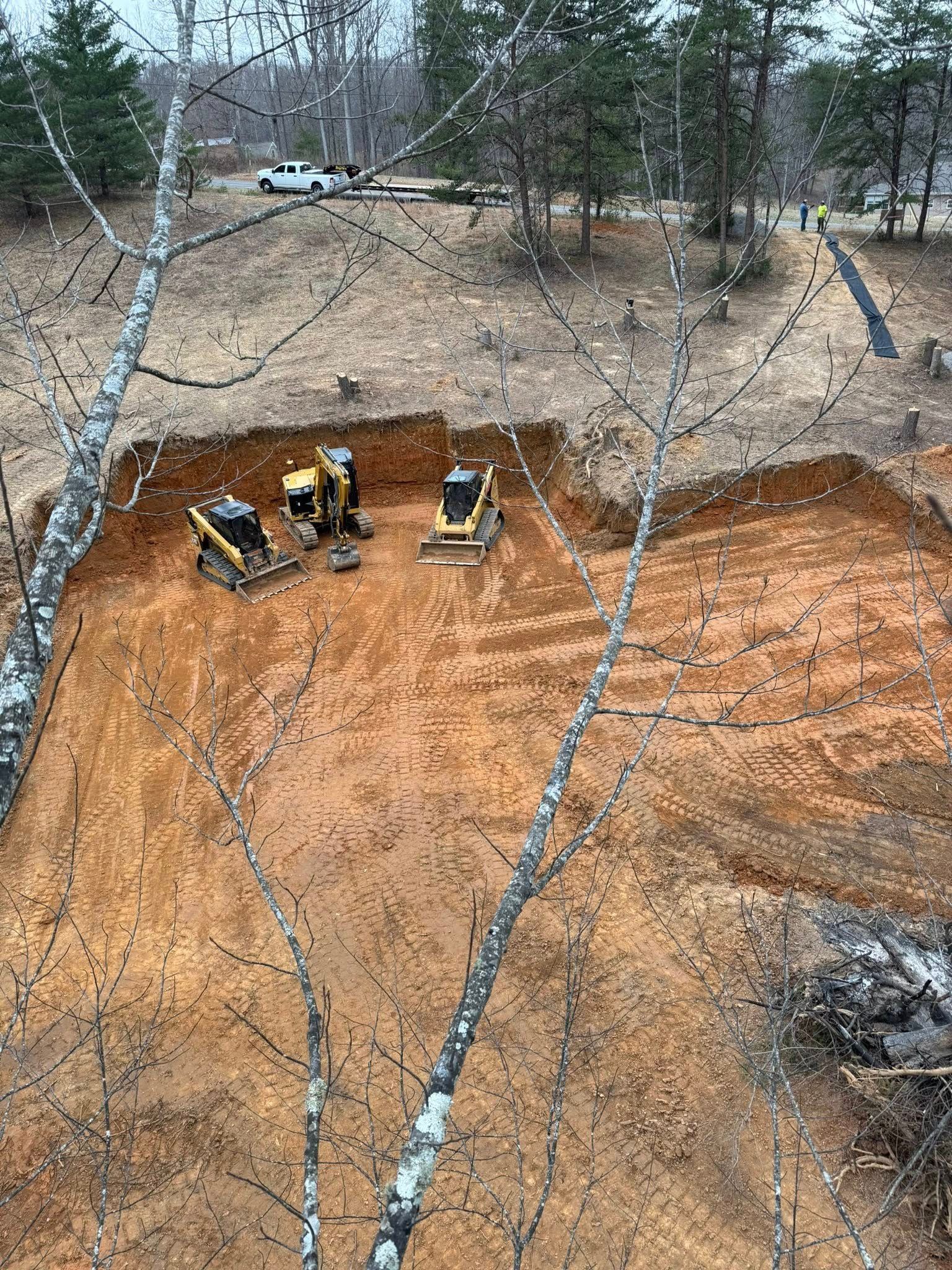 An aerial view of a construction site with a lot of dirt and trees in the background.