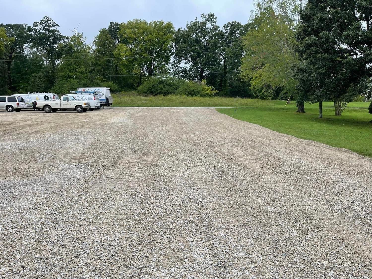 A gravel driveway with a lot of cars parked in it.