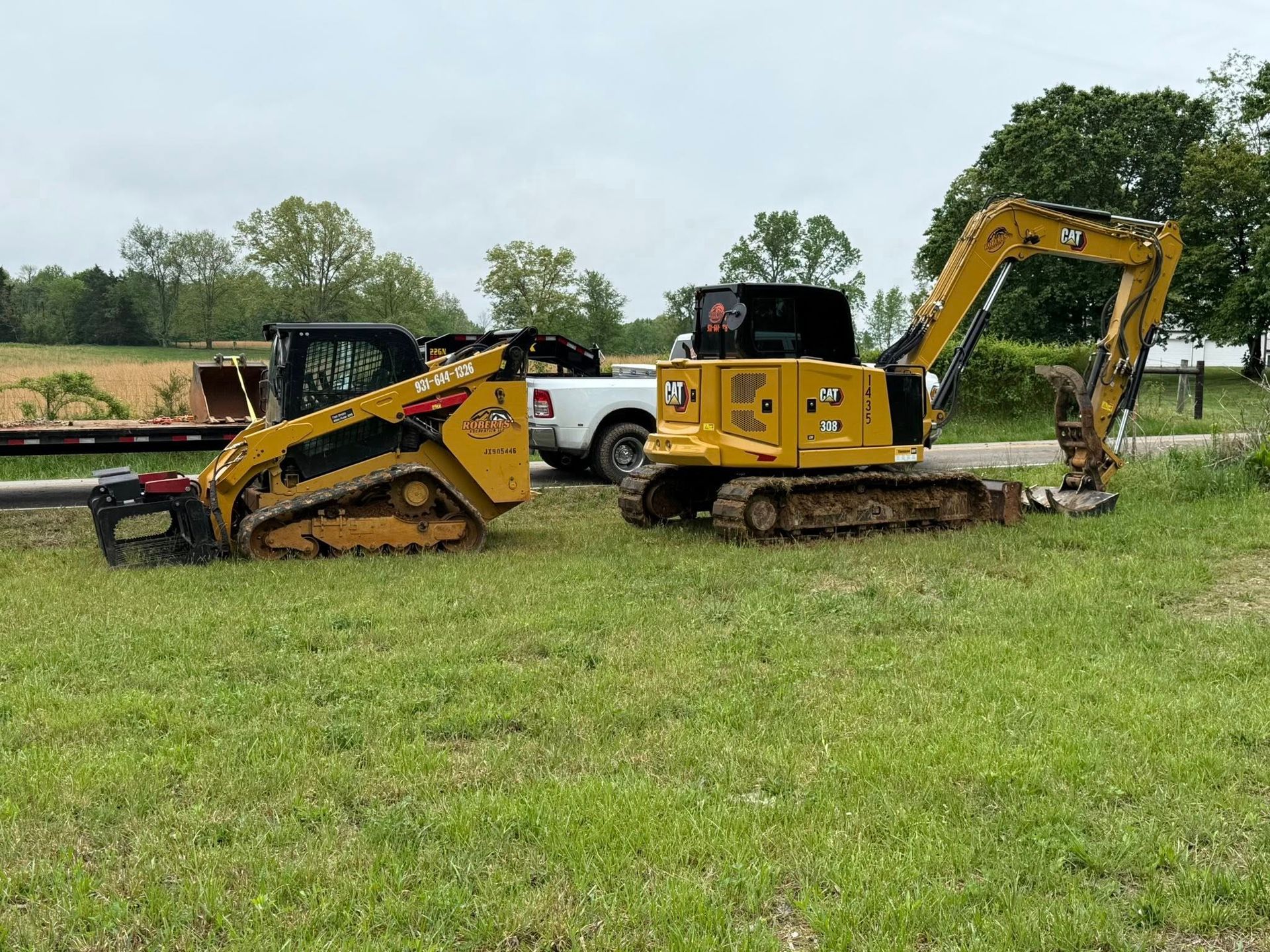 A bulldozer and an excavator are parked in a grassy field.