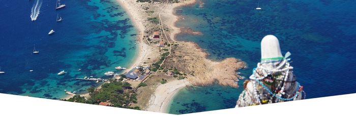 Vista aerea di una striscia di spiaggia in Croazia, con acqua azzurra e barche. Una struttura si trova sul lato destro dell'inquadratura.