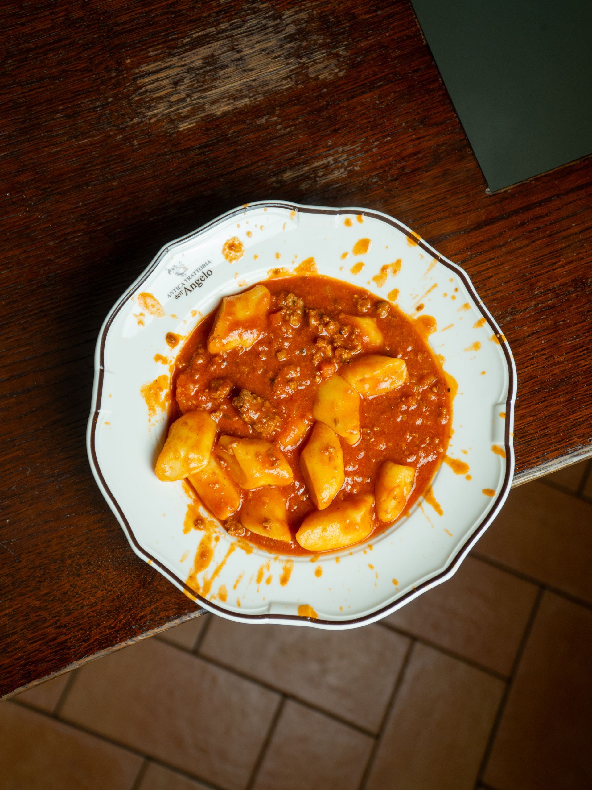 Piatto di gnocchi al ragù su un tavolo di legno, primo piano.