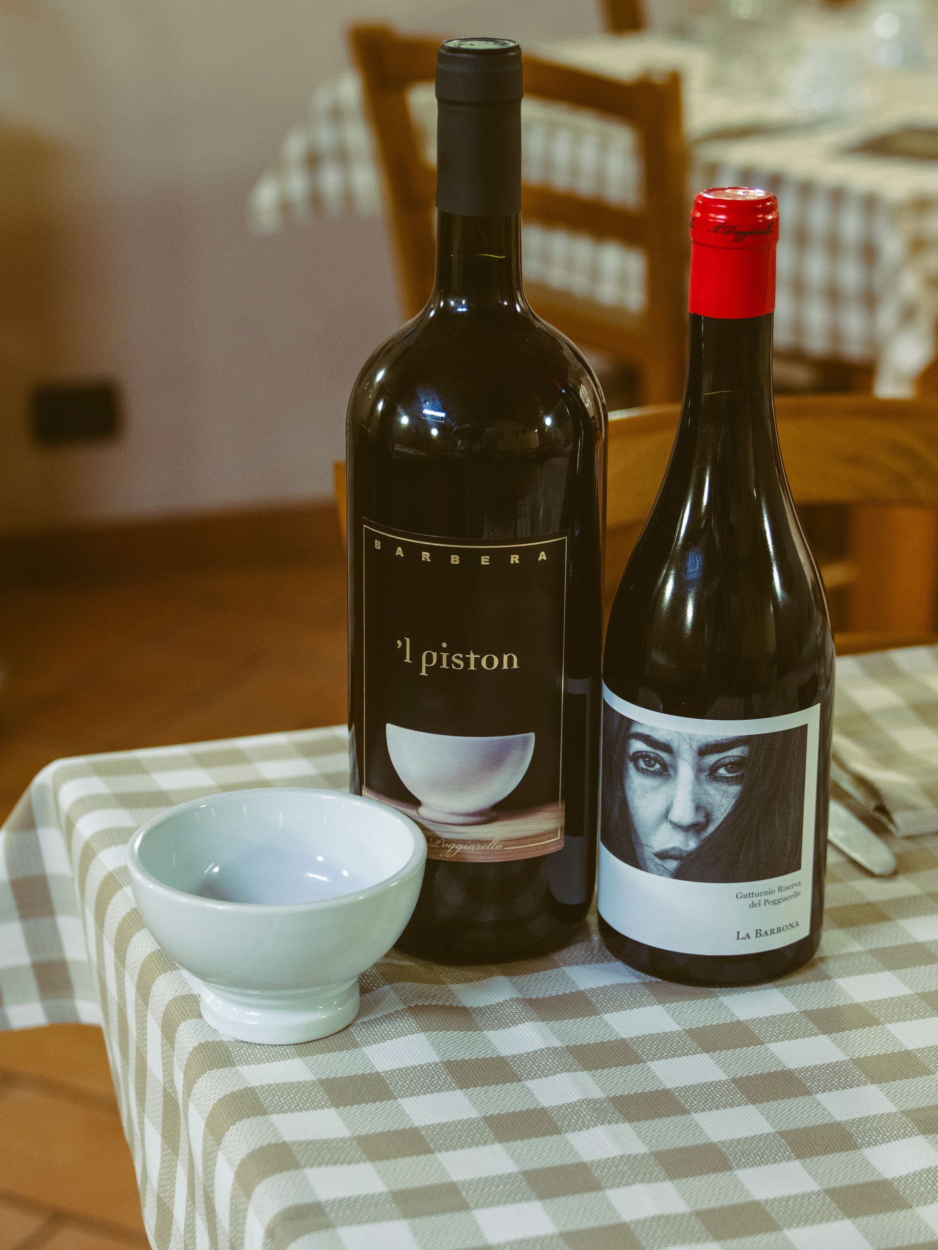 Due bottiglie di vino e una piccola ciotola su una tovaglia a quadri in un ristorante.