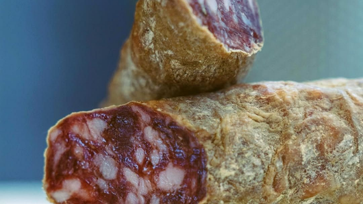 Tavolo del ristorante apparecchiato con uova, pane, vino e salse su una tovaglia a quadri.