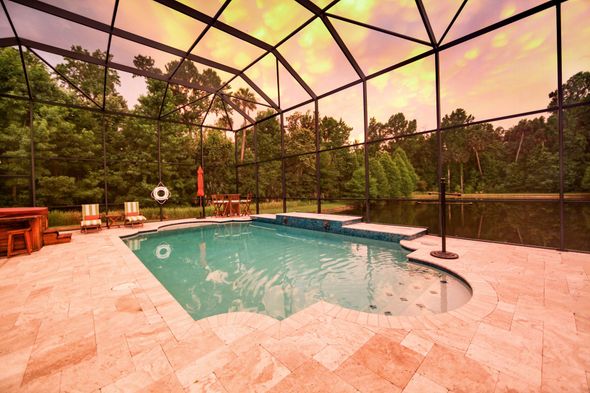 A large swimming pool is surrounded by a screened in area