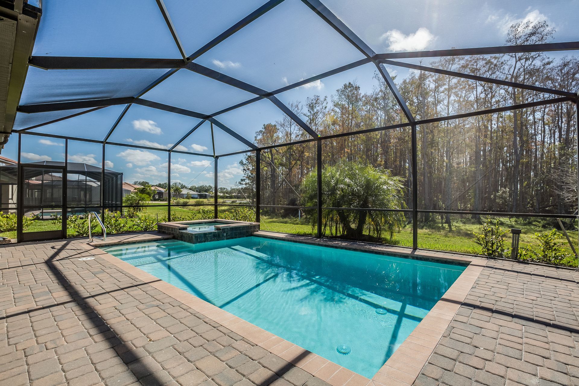 A large swimming pool is surrounded by a screened in area