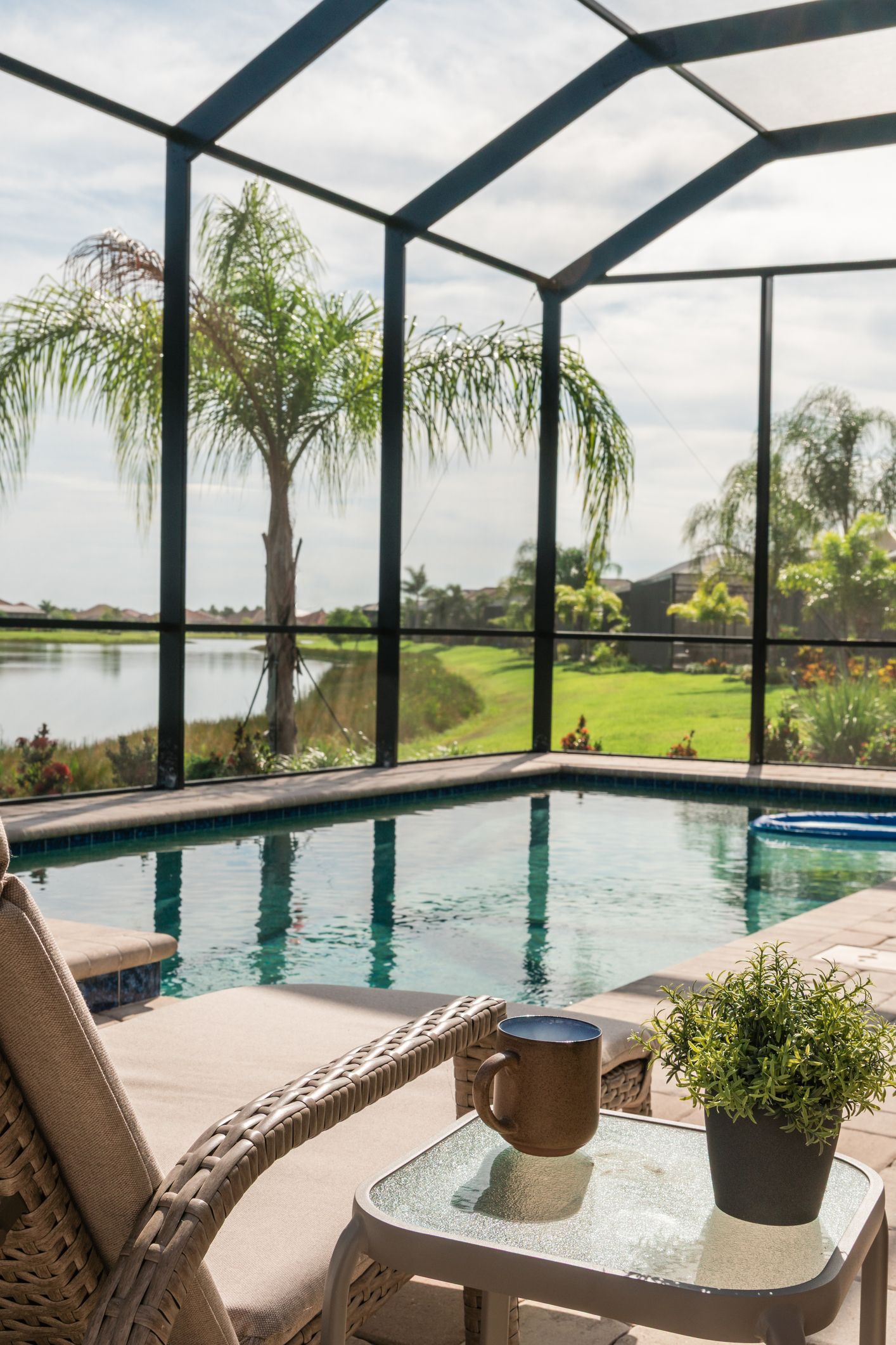 A screened in area with a swimming pool and chairs