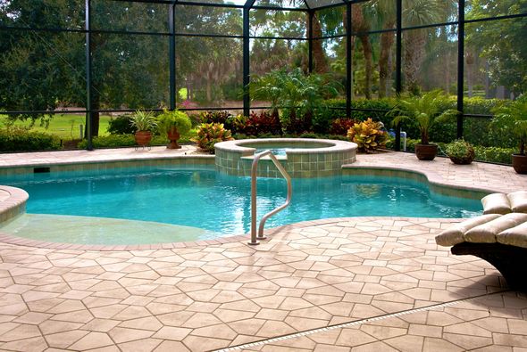A large swimming pool is surrounded by a screened in area
