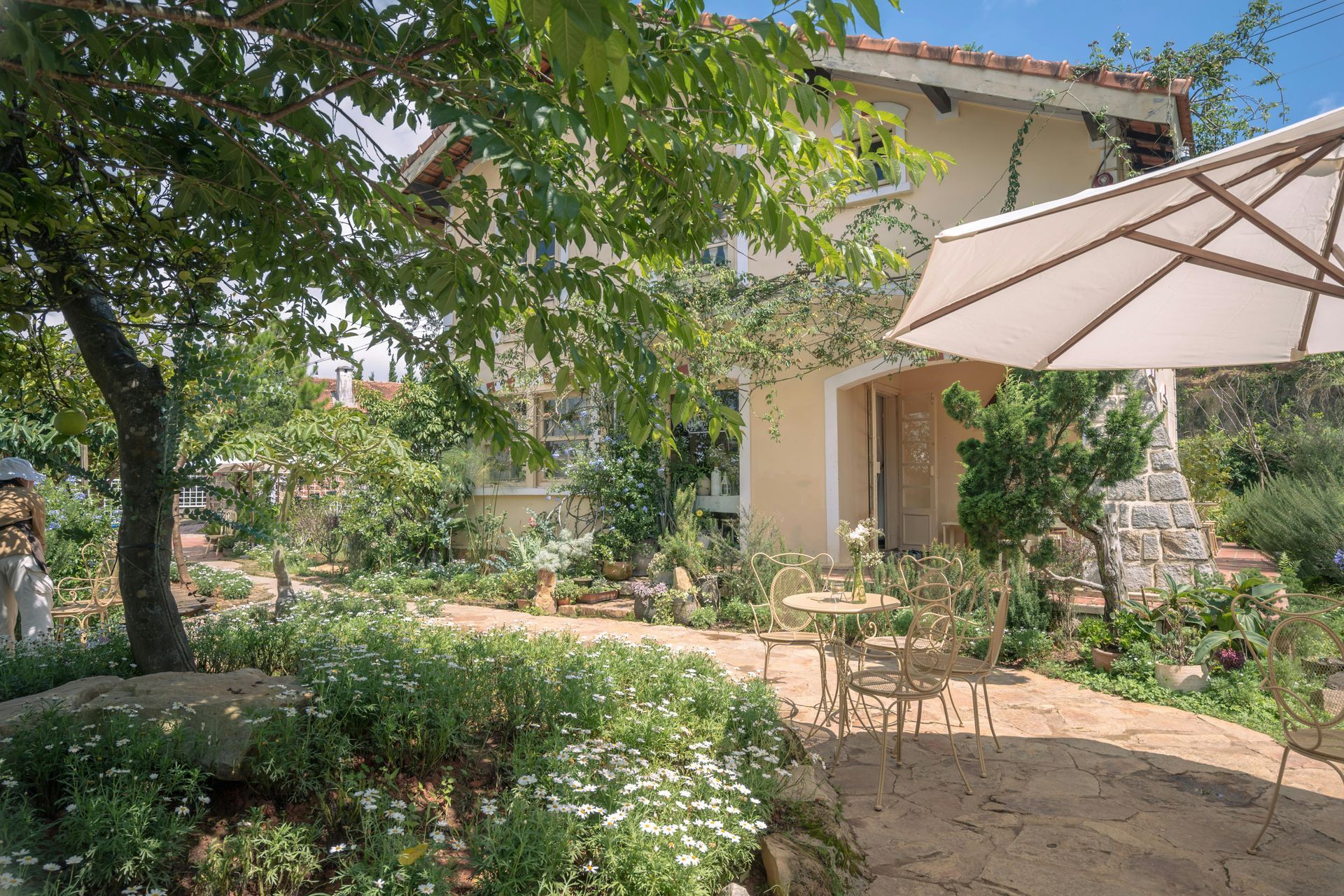 A white umbrella is sitting on a patio in front of a house.