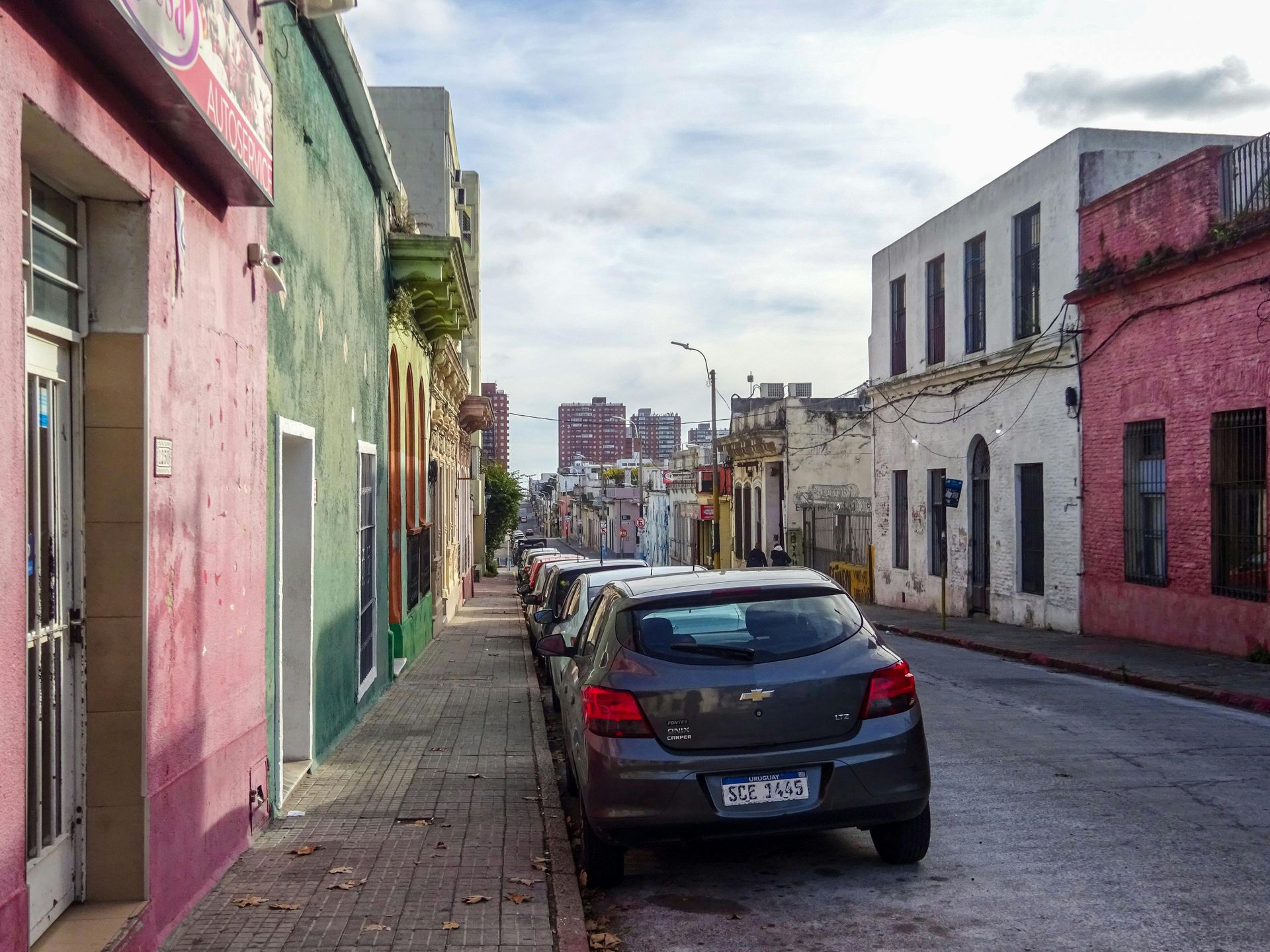 A row of cars are parked on the side of a city street.