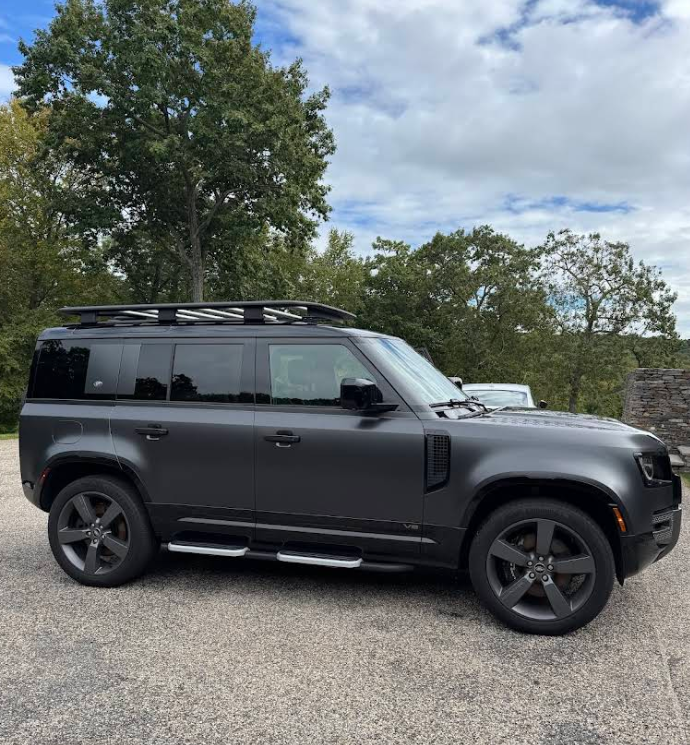 A black suv with a roof rack is parked in a parking lot