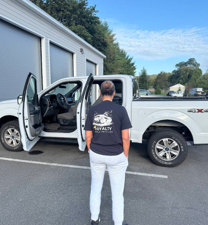 A woman standing in front of a white truck with the door open