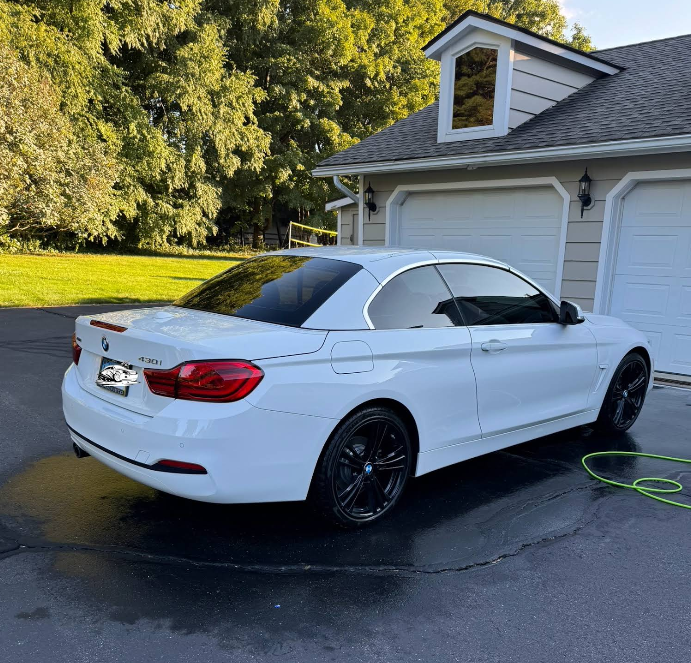 A white car is parked in a driveway in front of a garage.