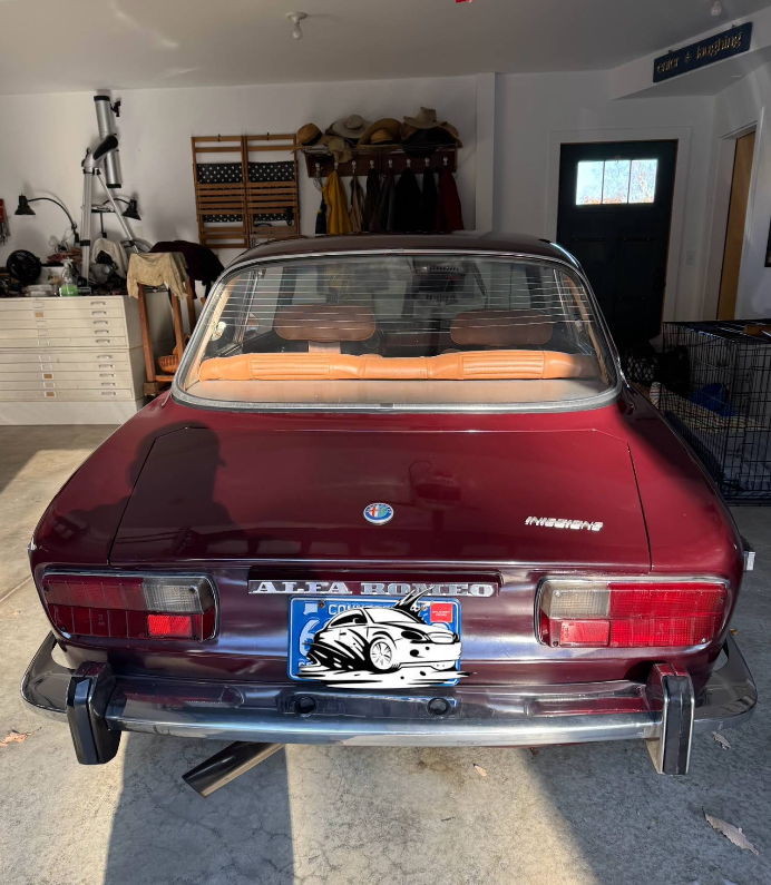 A red alfa romeo is parked in a garage